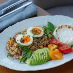 Delicious quinoa salad with sliced avocado, soft-boiled eggs, and fresh herbs.